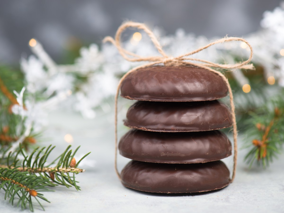 Rezept für Lebkuchen: 4 Nürnberger Lebkuchen gestapelt und mit einem Band zusammengebunden, dahinter Weihnachtsdeko.