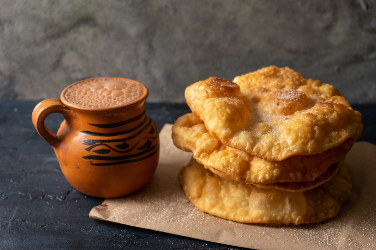 BuÃ±uelos: mexikanische Weihnachtskrapfen neben einer Tasse mexikanischer heiÃŸer Schokolade.