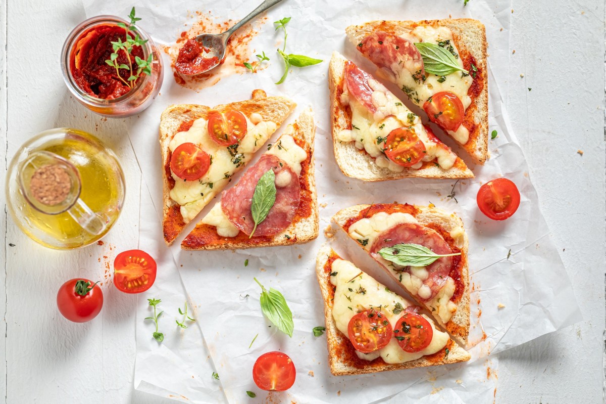 Überbackene Mozzarella-Toasts, umgeben von Zutaten.