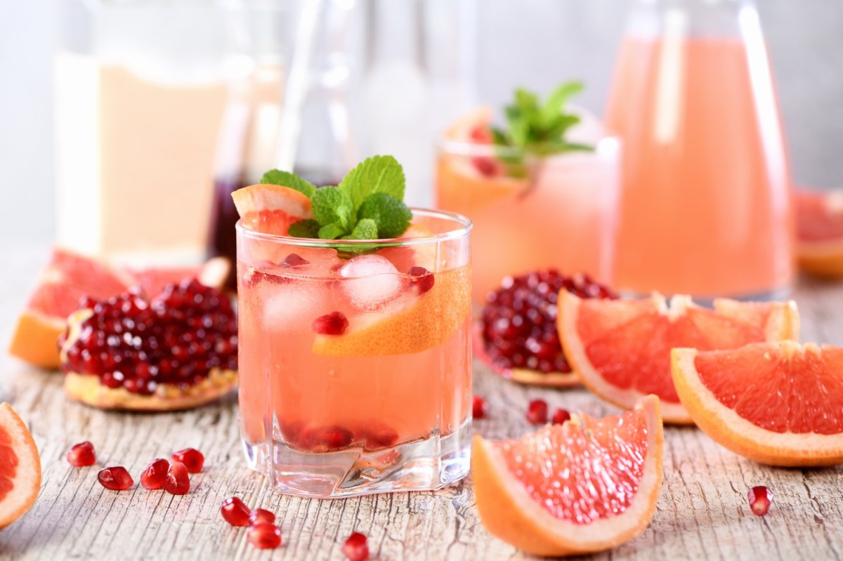 Mehere Gläser und eine Karaffe Grapefruit-Granatapfel-Mocktail, daneben liegen die Zutaten.