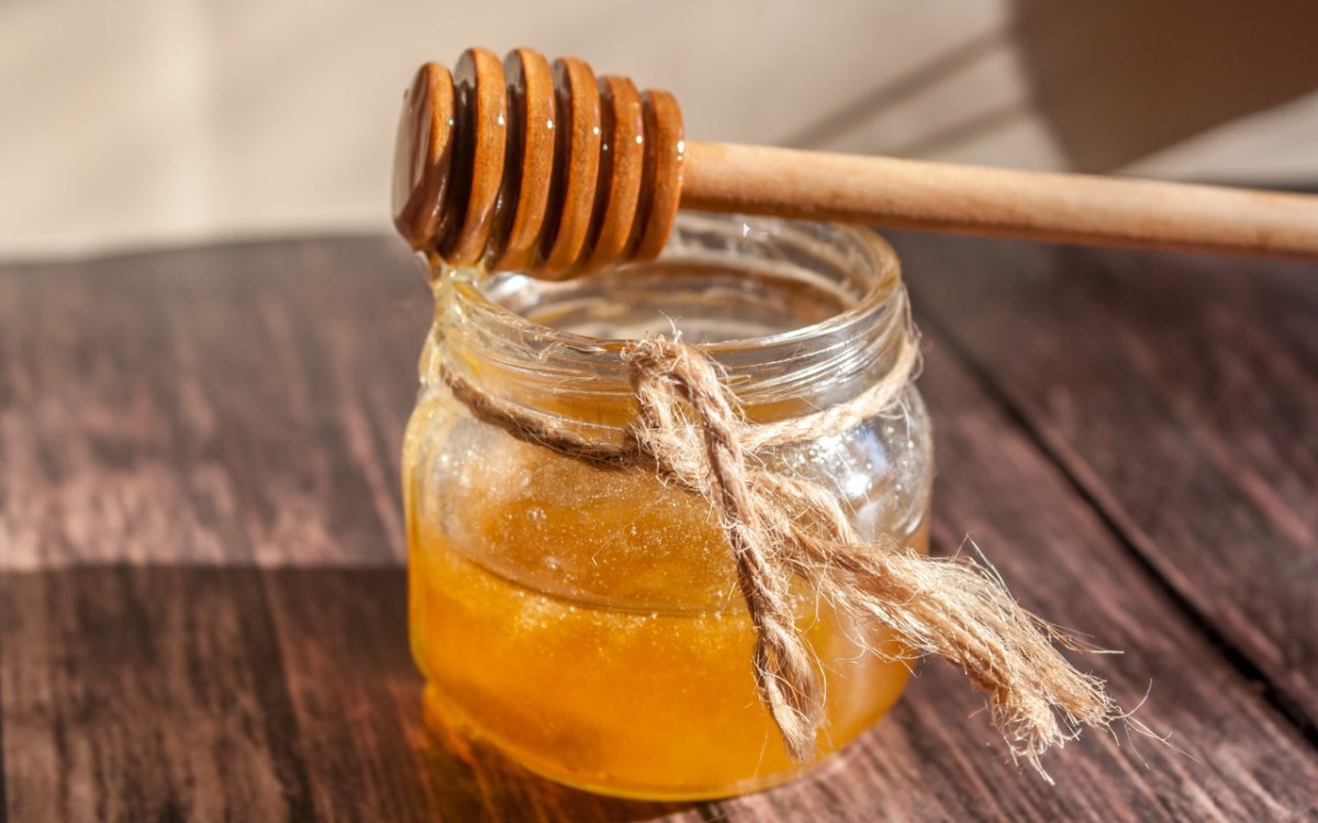 Ein Holzlöffel liegt auf einem Glas Honig.