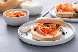 Räucherlachs-Bagels mit Kapern und Dill auf mehreren Tellern.