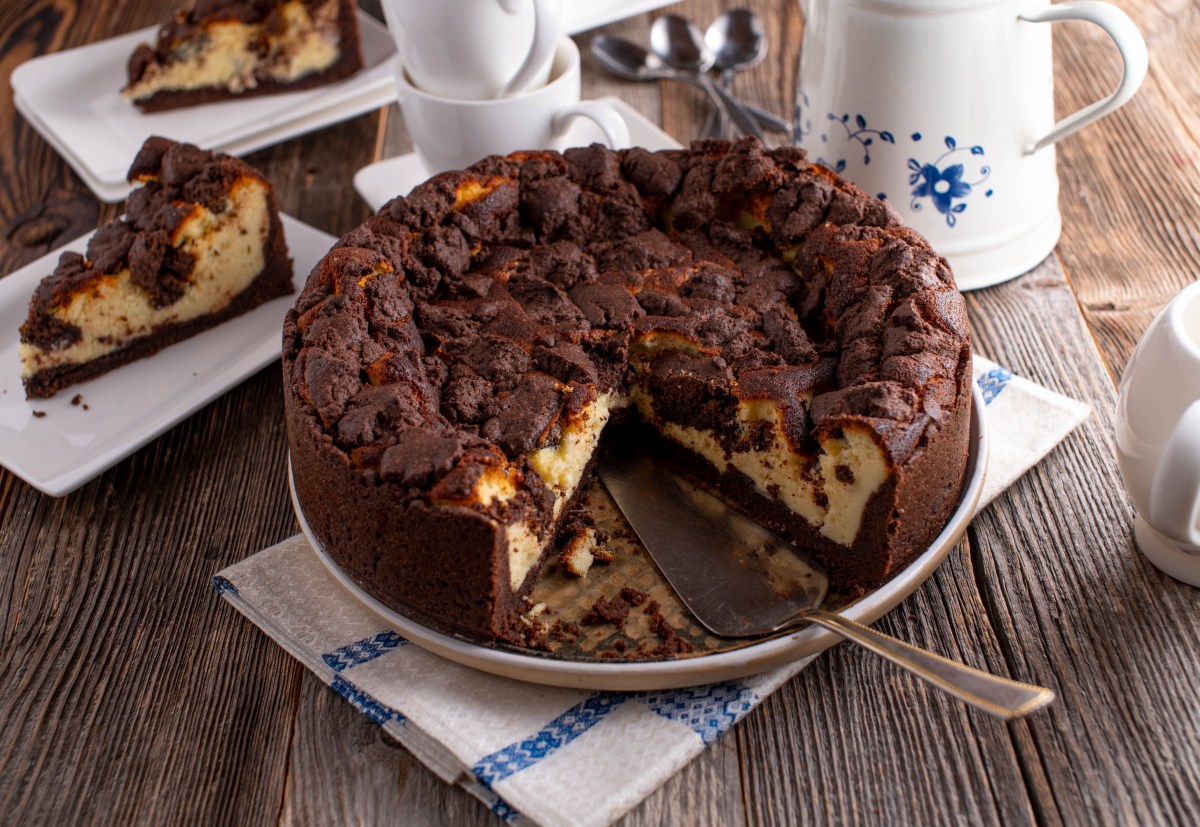 Ein veganer Zupfkuchen auf einem Kuchenteller, zwei Stücke wurde schon entnommen und liegen dahinter auf zwei Tellern.