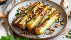 Ein Teller Lauch aus der Heißluftfritteuse mit Haselnüssen und Kräutern bestreut. Nahaufnahme.