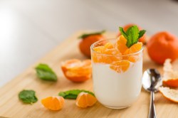 Glas mit Mandarinenquark und Mandarinen daneben