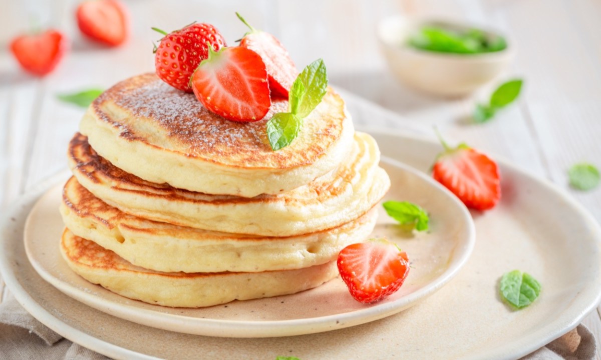 Ein Stapel Pancakes mit Buttermilch auf einem Teller, die mit Erdbeeren dekoriert sind.