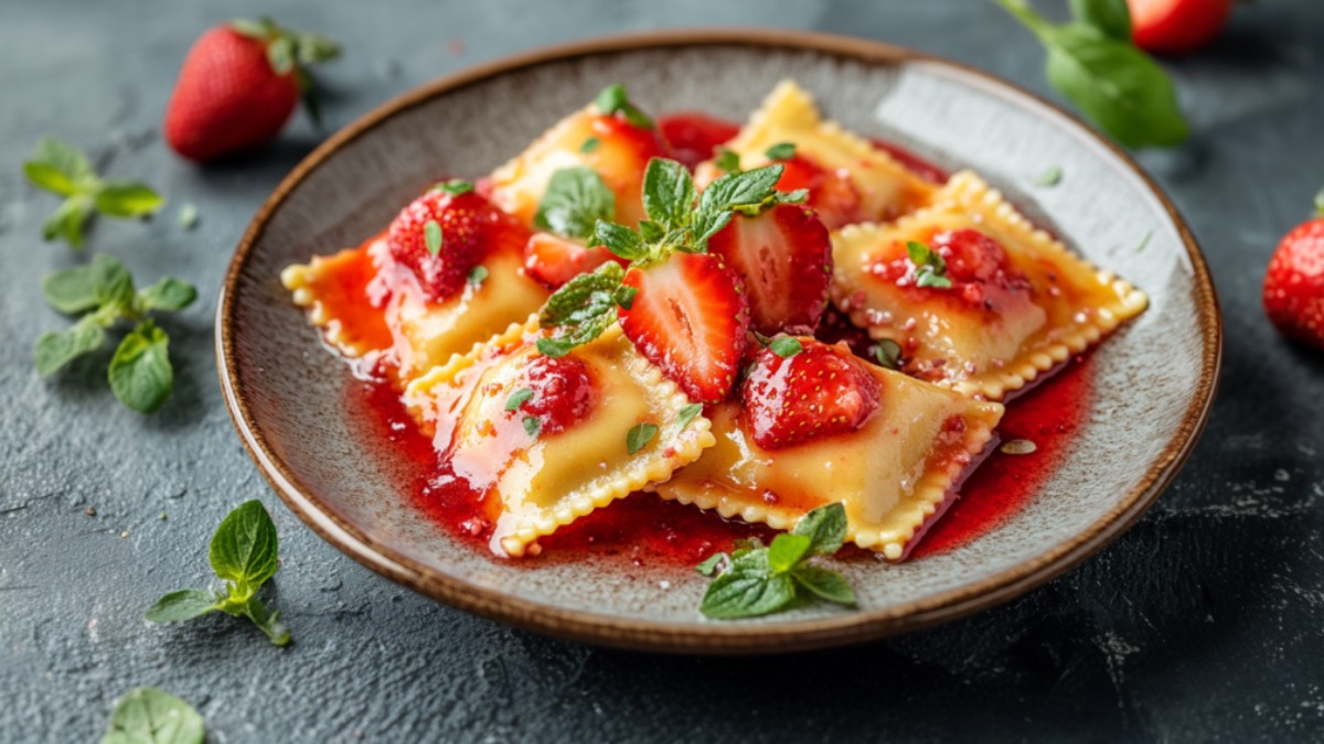 Süße Ravioli mit Erdbeerfüllung, Erdbeersoße und frischen Erdbeeren auf einem Teller.